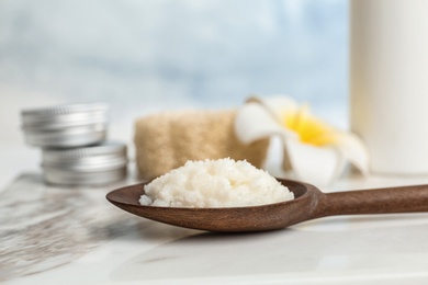 Photo of Spoon with Shea butter on marble table, closeup