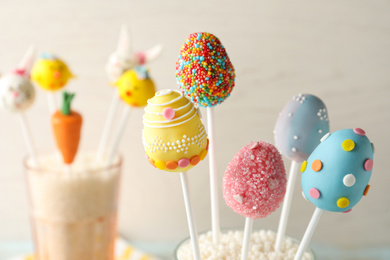 Photo of Egg shaped cake pops for Easter celebration on light background, closeup