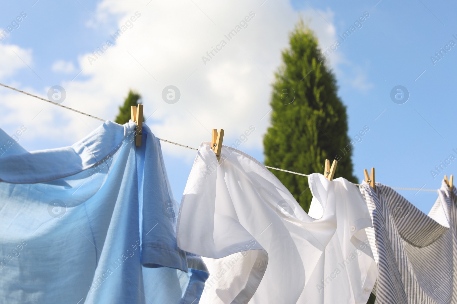Photo of Clean clothes hanging on washing line outdoors, closeup. Drying laundry