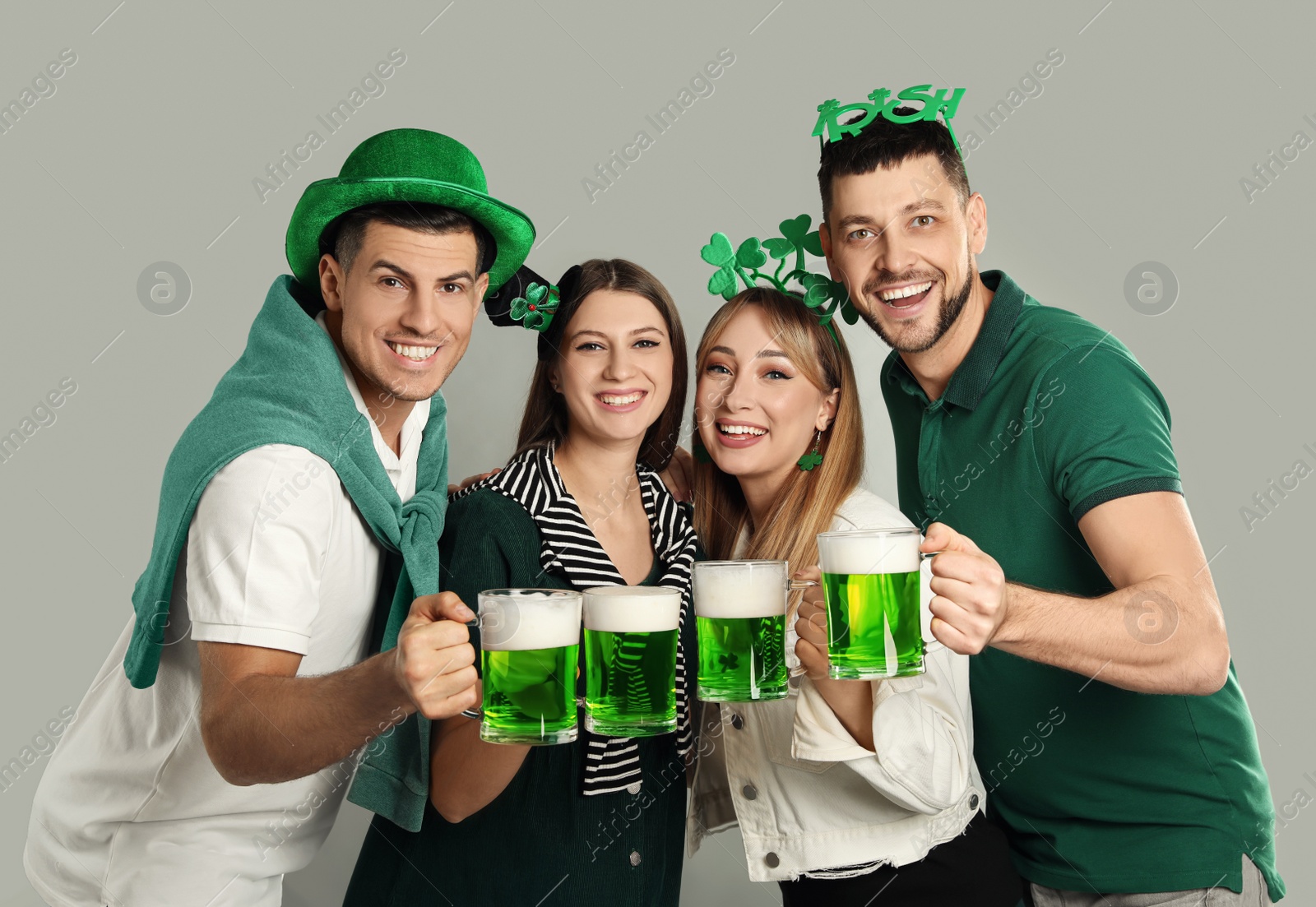 Photo of Happy people in St Patrick's Day outfits with beer on light grey background