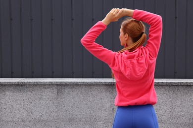 Photo of Woman in gym clothes doing exercises on street, back view. Space for text