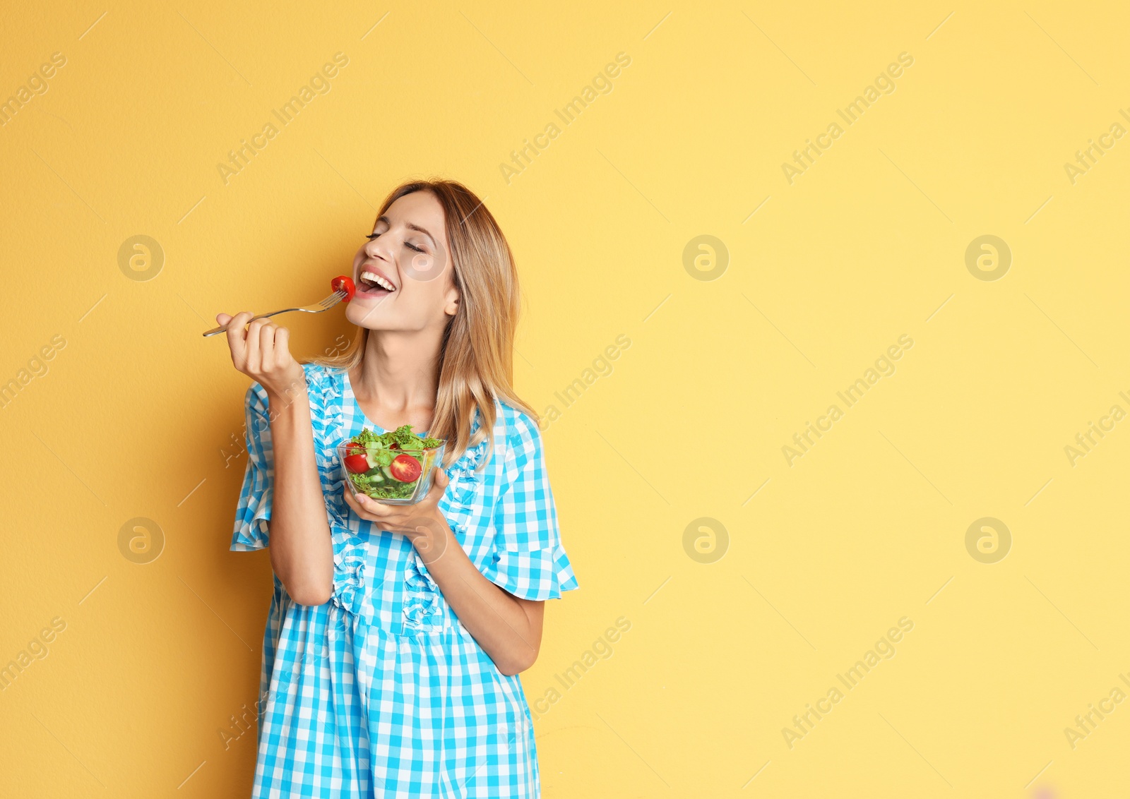 Photo of Happy slim woman with salad on color background. Weight loss diet