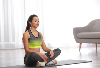 Photo of Young woman in fitness clothes doing exercise at home. Space for text