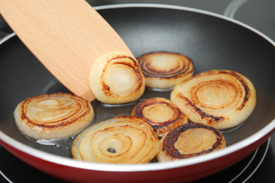 Photo of Cooking onion rings in frying pan, closeup