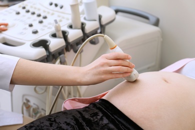 Photo of Pregnant woman undergoing ultrasound scan in clinic, closeup