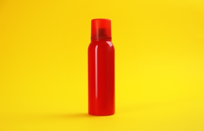 Photo of Bottle with insect repellent spray on yellow background