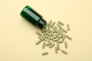 Photo of Vitamin pills and bottle on beige background, top view. Space for text
