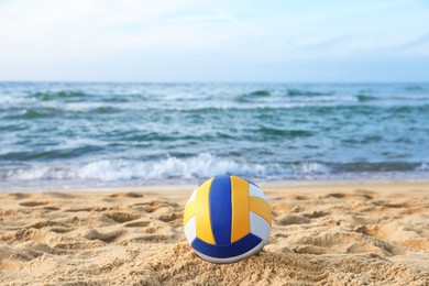 Photo of Colorful volleyball ball on sand near sea