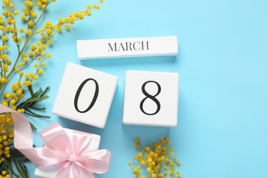 Photo of International Women's day - 8th of March. Gift box, wooden block calendar and beautiful flowers on light blue background, flat lay