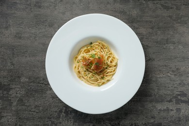 Photo of Tasty spaghetti with prosciutto and microgreens on grey textured table, top view. Exquisite presentation of pasta dish