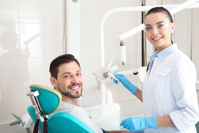 Photo of Professional dentist and happy patient in modern clinic