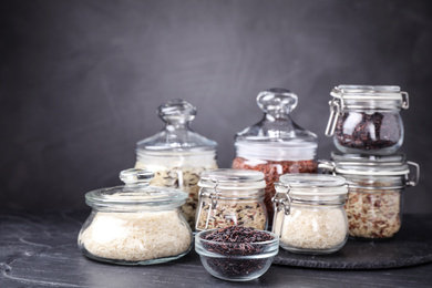 Photo of Brown and polished rice in jars on grey table