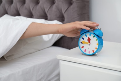 Photo of Man turning off alarm clock in bedroom