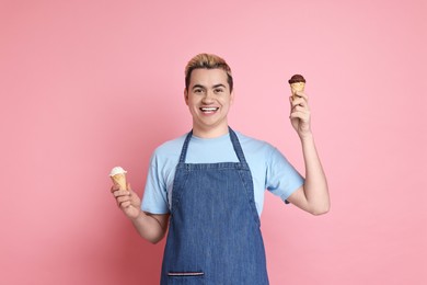Photo of Portrait of happy confectioner holding ice cream cones on pink background