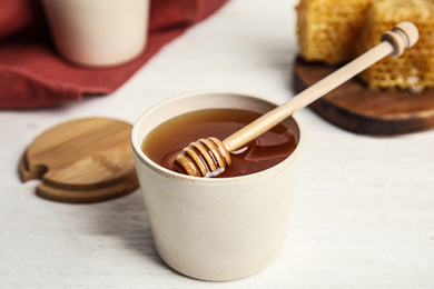 Photo of Jar of fresh honey and dipper on white wooden table