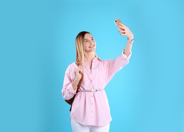 Photo of Teenage girl taking selfie on color background