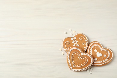 Photo of Tasty heart shaped gingerbread cookies on white wooden table, flat lay. Space for text