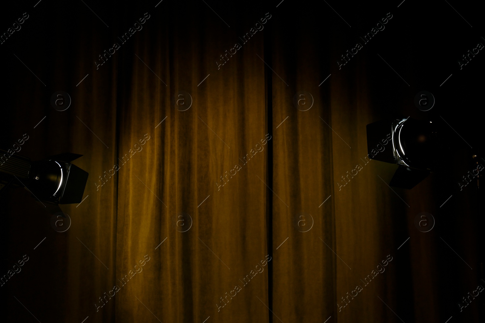 Photo of Theater curtains illuminated by spotlights in darkness