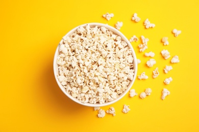 Photo of Paper bucket with tasty fresh popcorn on color background, top view