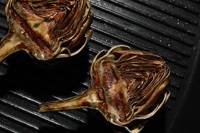 Photo of Pan with tasty grilled artichokes, closeup view