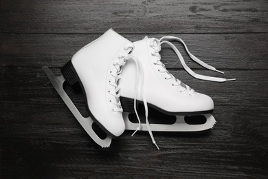 Photo of Pair of skates on black wooden background, flat lay