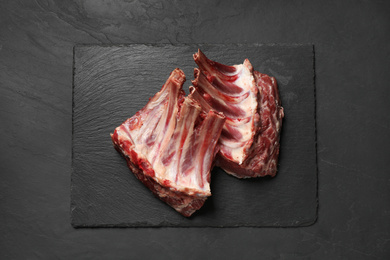 Raw ribs on black table, top view