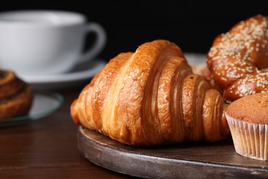 Photo of Freshly baked croissant and other pastries on wooden table, closeup. Space for text