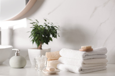 Composition with soap dispenser and towels on white table indoors