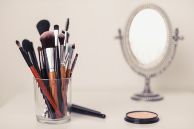 Holder with makeup brushes on table