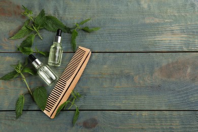 Photo of Stinging nettle, extract and comb on blue wooden background, flat lay with space for text. Natural hair care