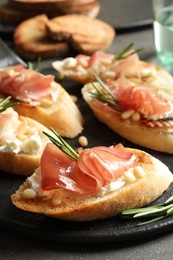 Tasty bruschettas with prosciutto and cream cheese served on table, closeup