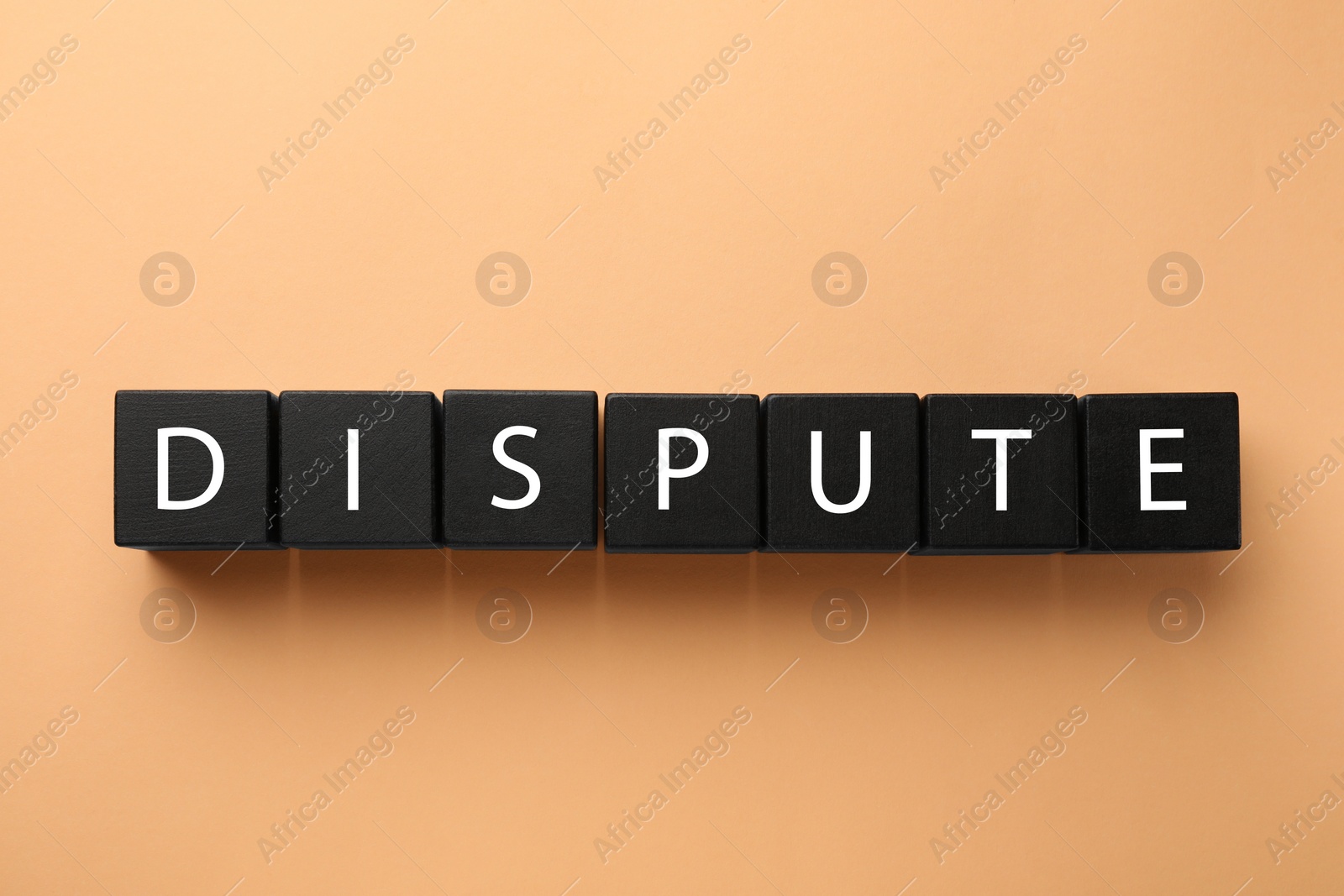 Photo of Black cubes with word Dispute on pale orange background, top view