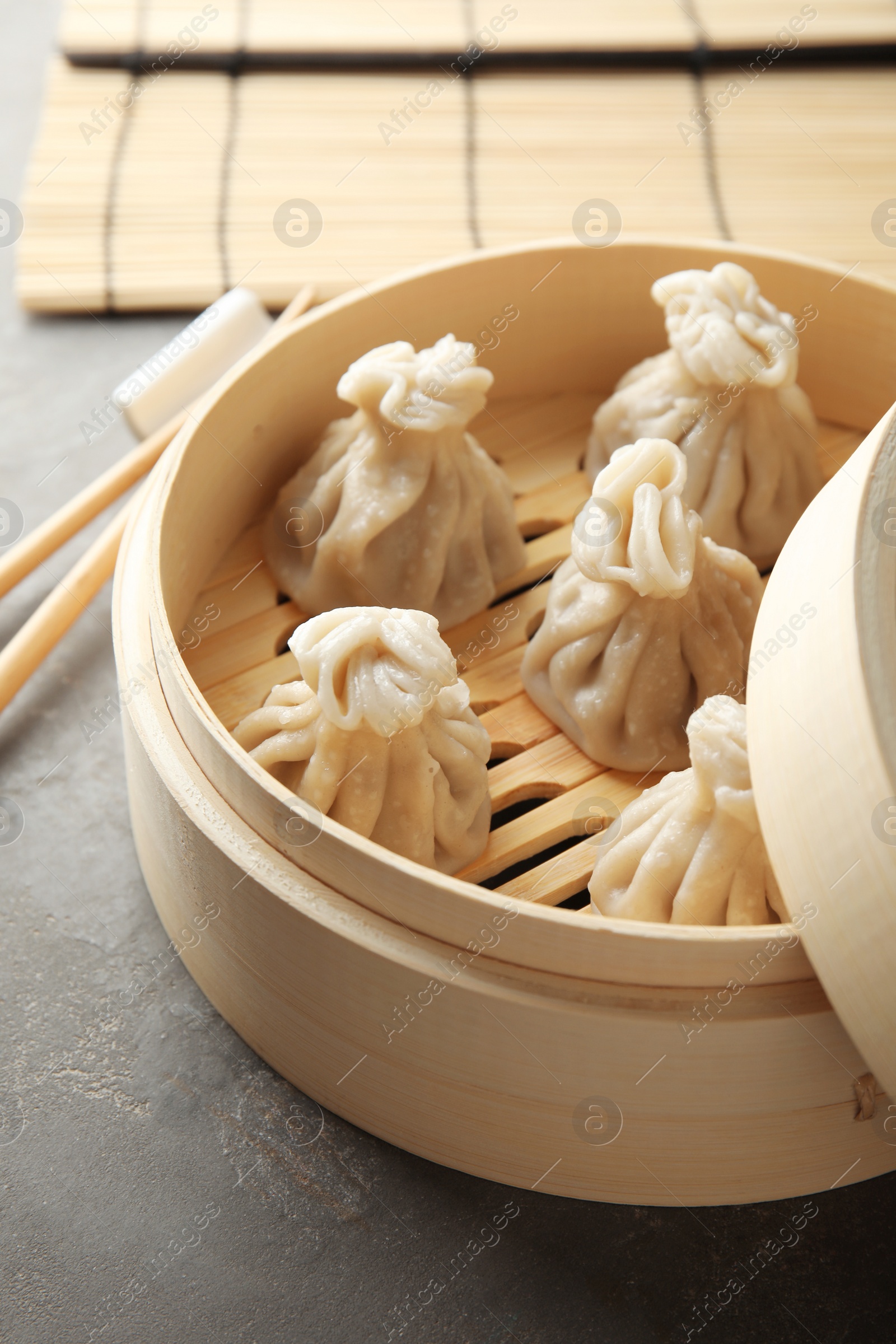 Photo of Bamboo steamer with tasty baozi dumplings on table