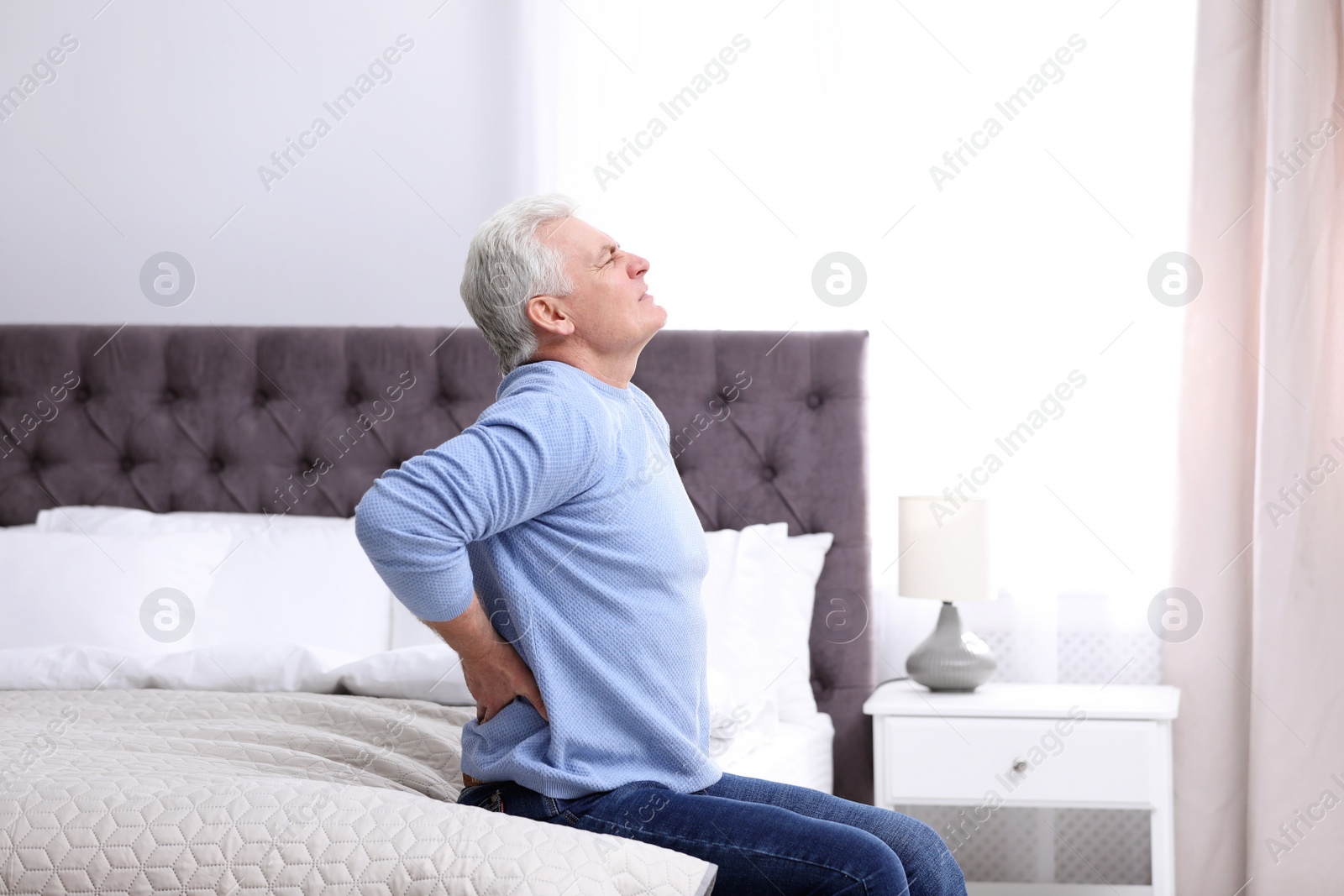 Photo of Senior man suffering from back pain at home