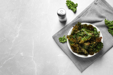 Tasty baked kale chips on grey marble table, flat lay. Space for text