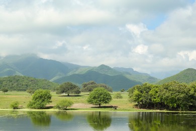 Picturesque view of mountains and green meadow with lake