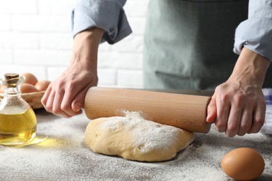 Photo of Woman rolling raw dough at table, closeup