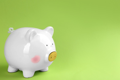 White piggy bank on green background. Space for text