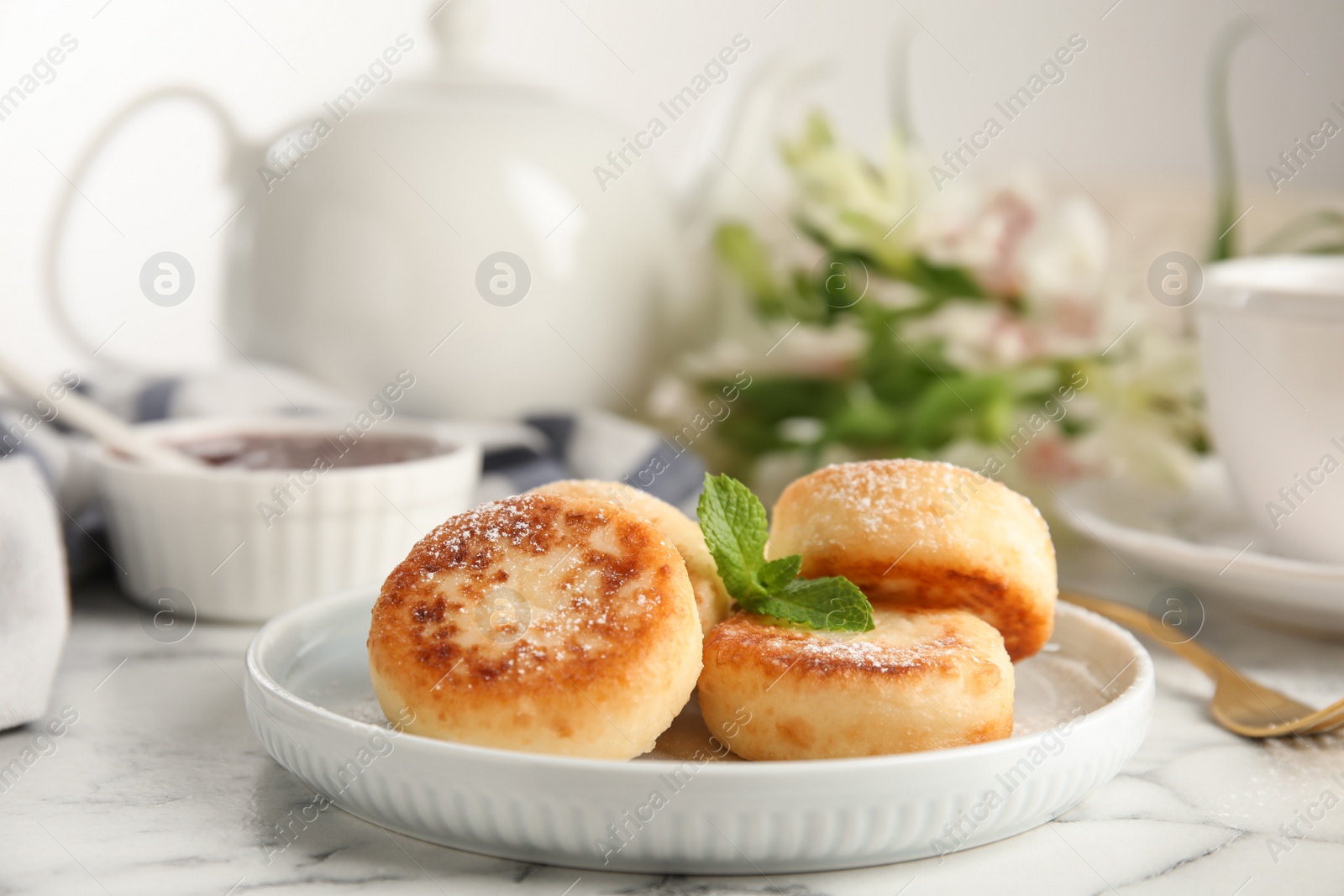 Photo of Delicious cottage cheese pancakes with mint and icing sugar on white marble table