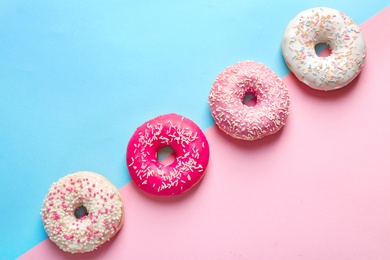 Photo of Delicious doughnuts with sprinkles on color background, top view