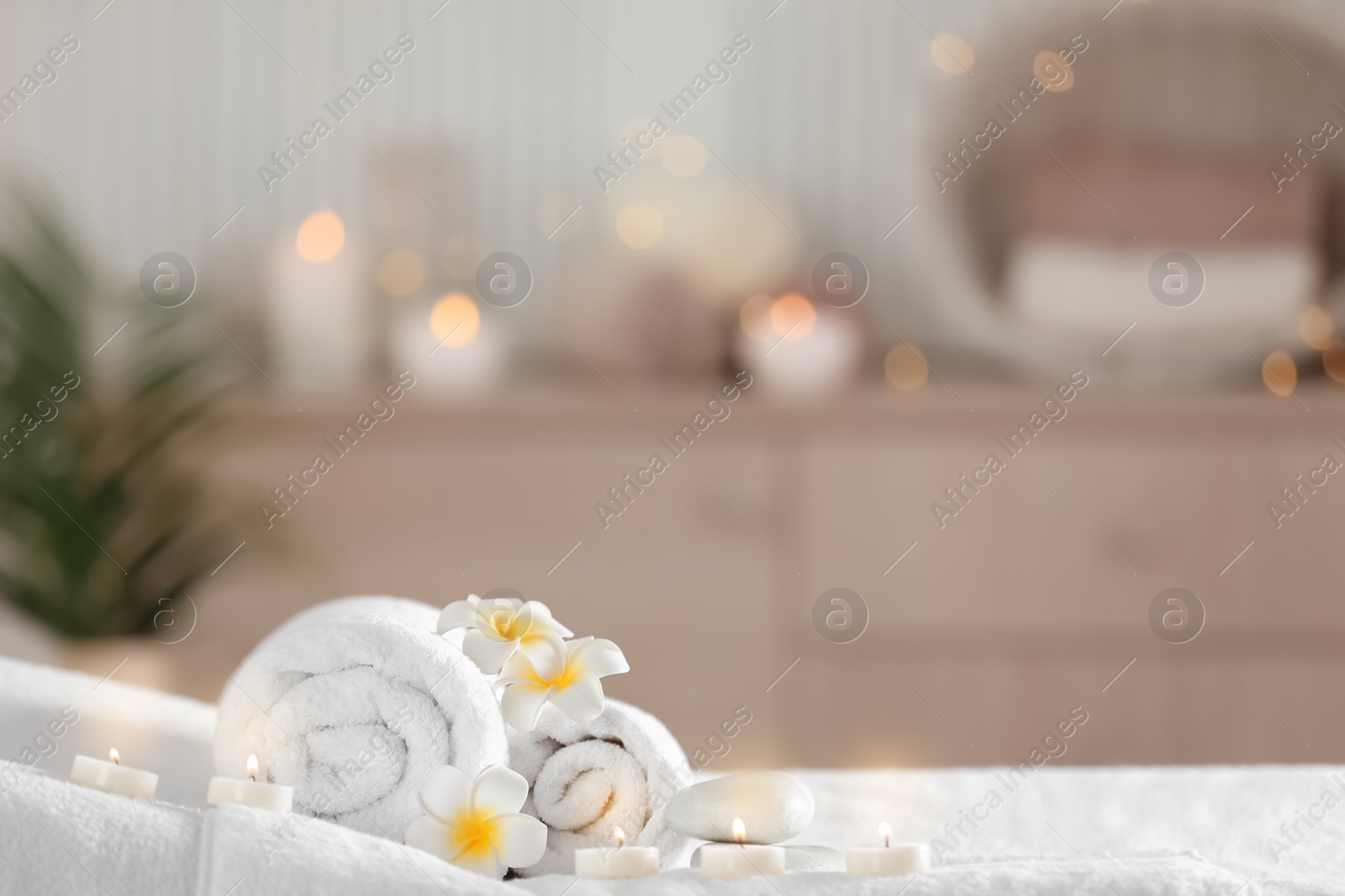 Photo of Towels and candles on massage table in modern spa salon. Place for relaxation