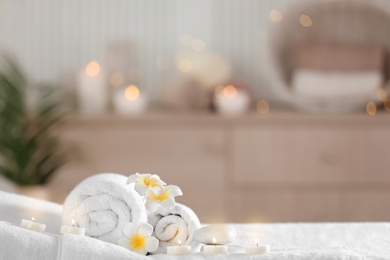 Photo of Towels and candles on massage table in modern spa salon. Place for relaxation