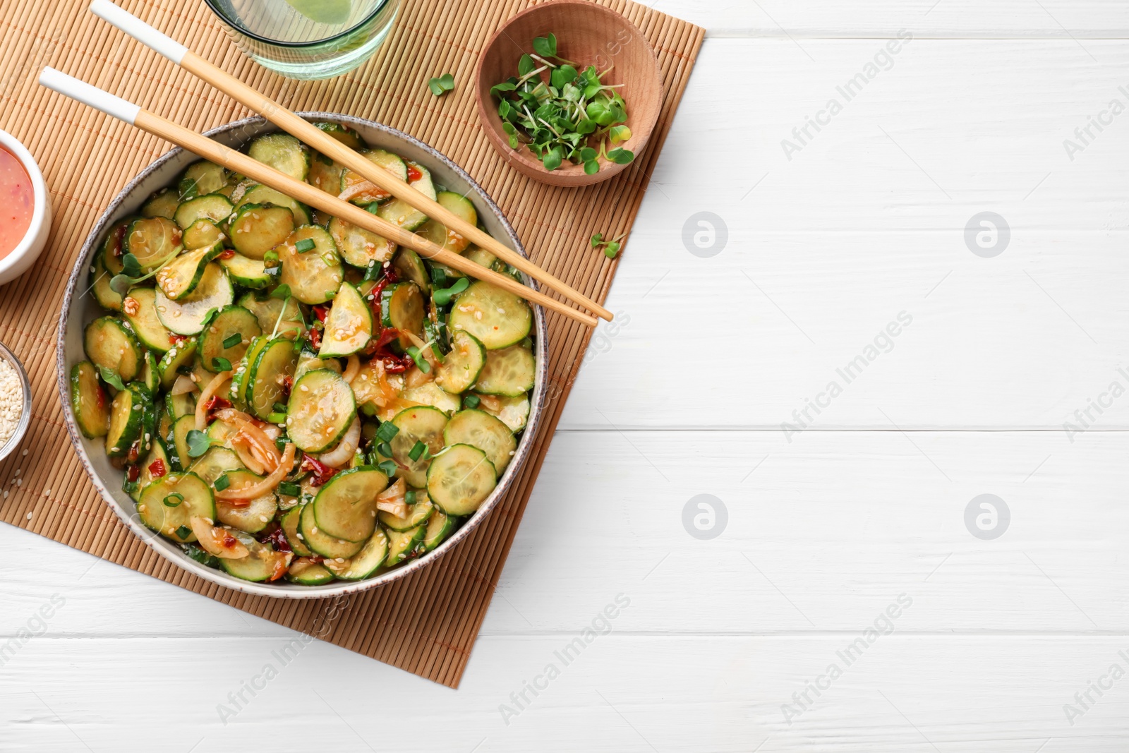 Photo of Bowl of delicious cucumber salad served on white wooden table, flat lay. Space for text