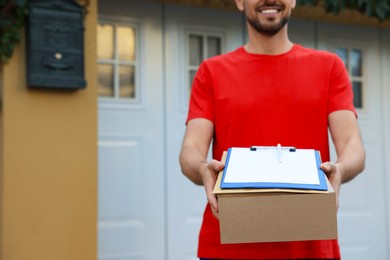 Photo of Courier in uniform holding order receipt and parcel outdoors, closeup. Space for text
