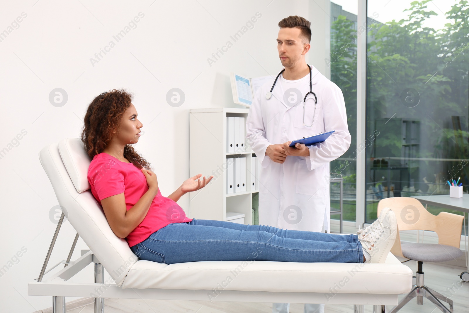 Photo of Male doctor working with African American patient in hospital