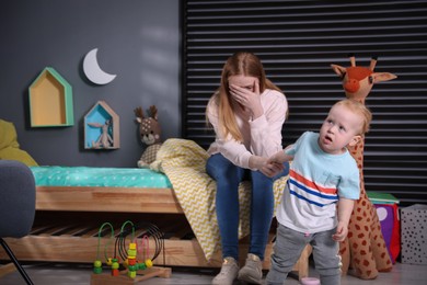 Photo of Depressed single mother with baby in children's room