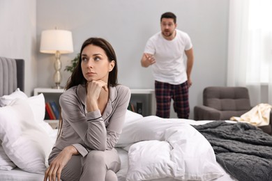 Photo of Offended wife ignoring her angry husband in bedroom, selective focus. Relationship problems