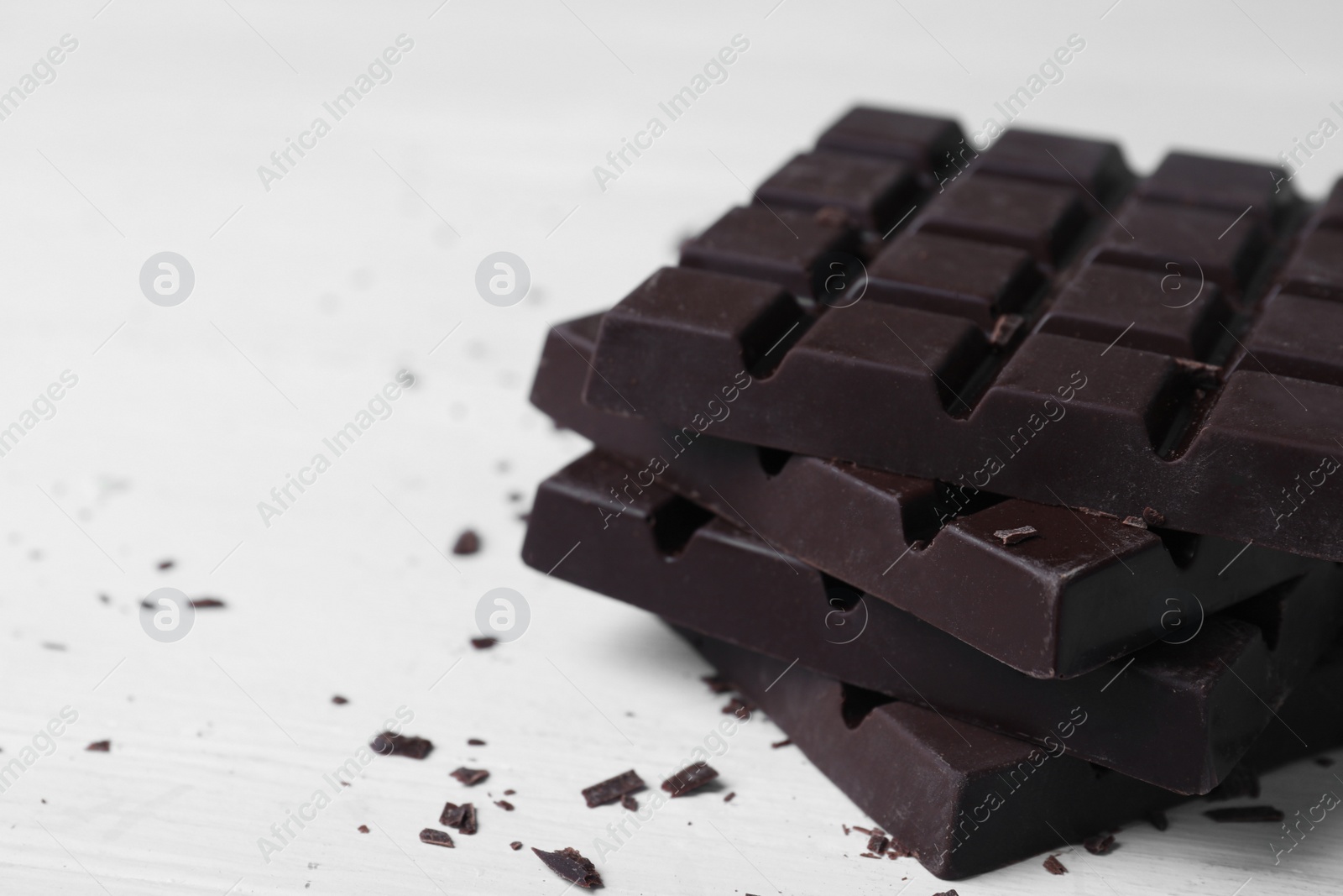 Photo of Tasty dark chocolate bars on white table, closeup