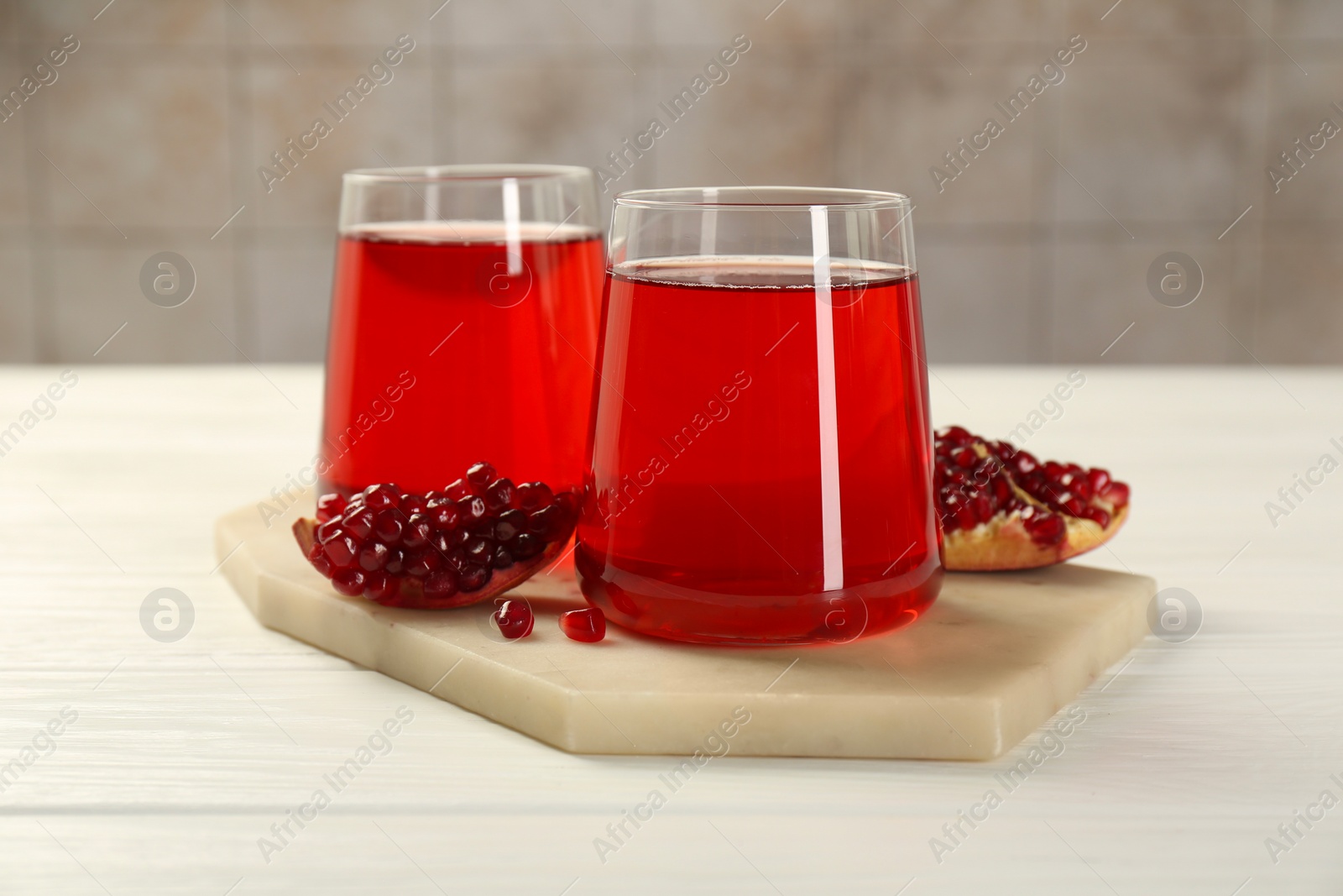 Photo of Tasty pomegranate juice in glasses and fresh fruit on white wooden table