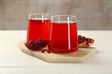 Photo of Tasty pomegranate juice in glasses and fresh fruit on white wooden table